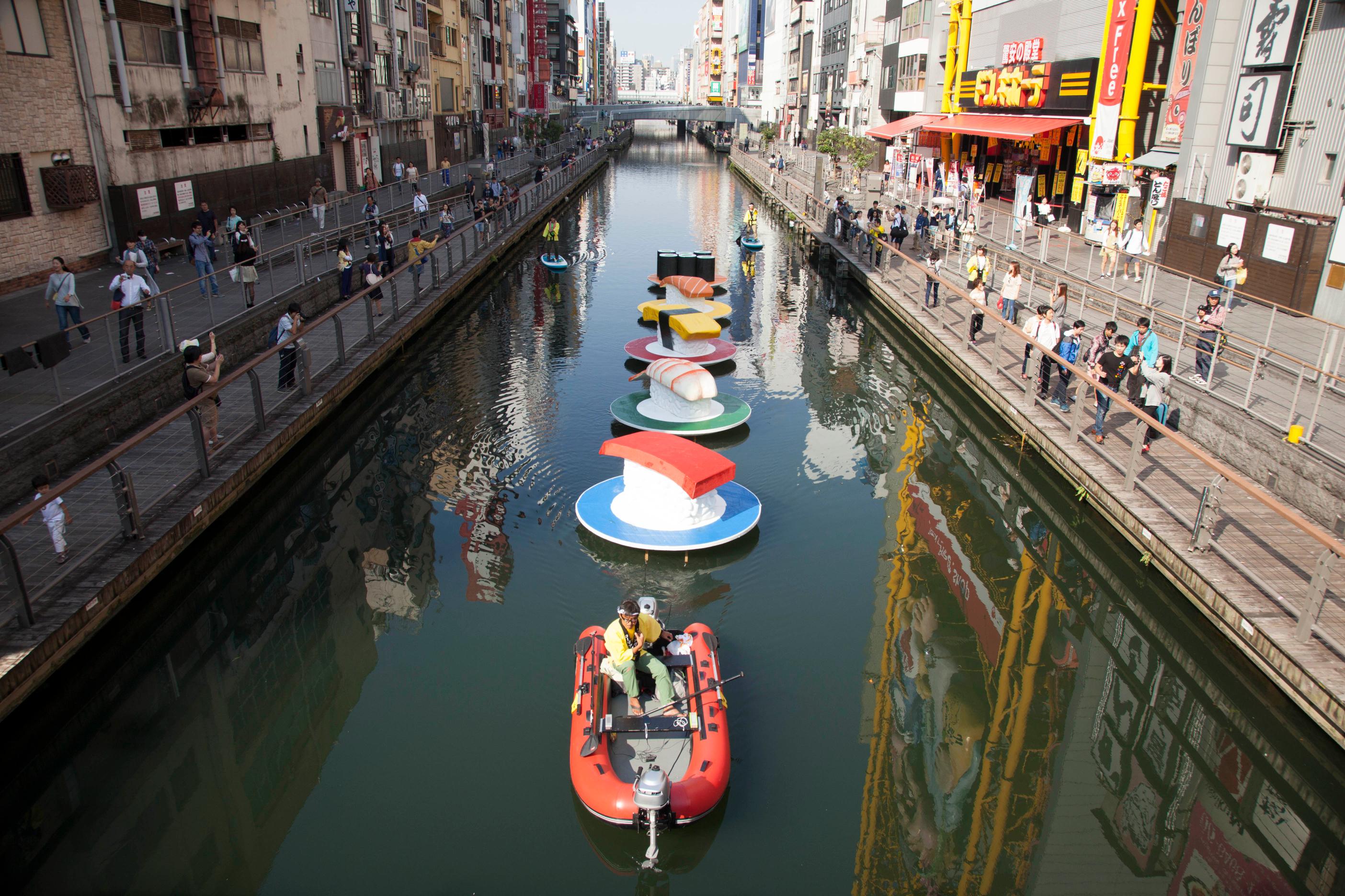 2015選定作品「ローリングスシー」：川面に寿司オブジェを流し、川を巨大な回転寿司の舞台にしてしまおうというプロジェクト。水門で水位を安定させ、川面に近づける遊歩道を整備してきたからこそ実現できた作品