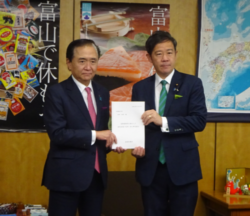画像：田畑総務副大臣（右）に緊急提言を手交する黒岩委員長（左）